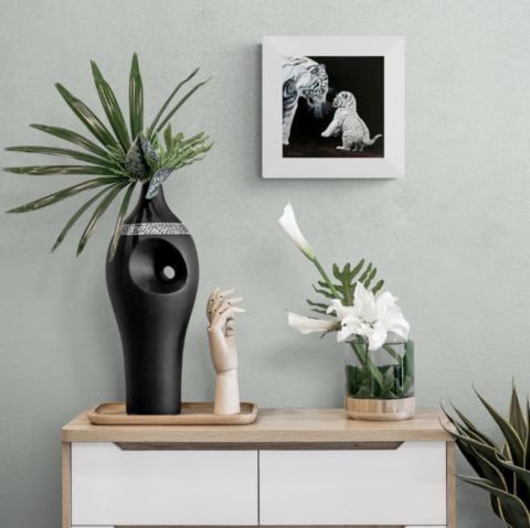 Painting of white tigers displayed above a chest of drawers with plants by wildlife artist Laurence Saunois